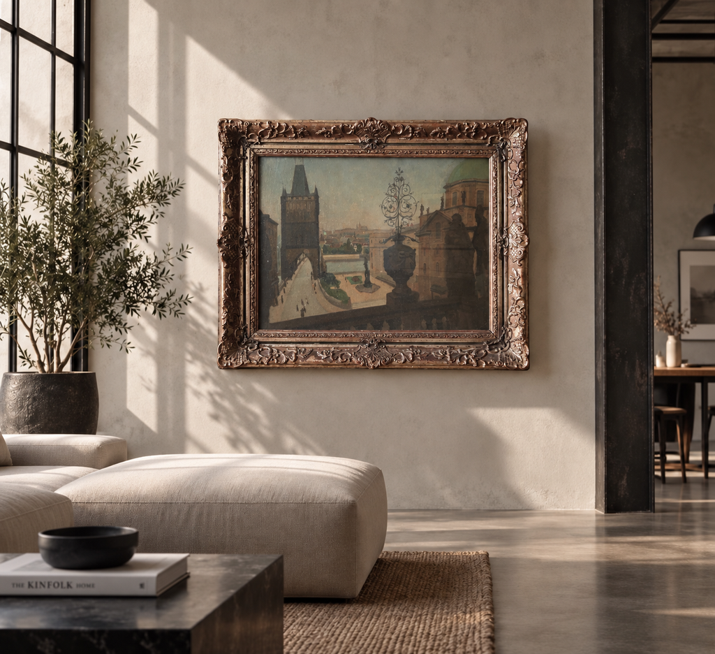 AI vizualizace: pražský obraz v ornamentálním rámu v moderním interiéru. Ilustrační prostředí, nikoli dokumentace stavu. AI interior visualization; not a condition photograph.